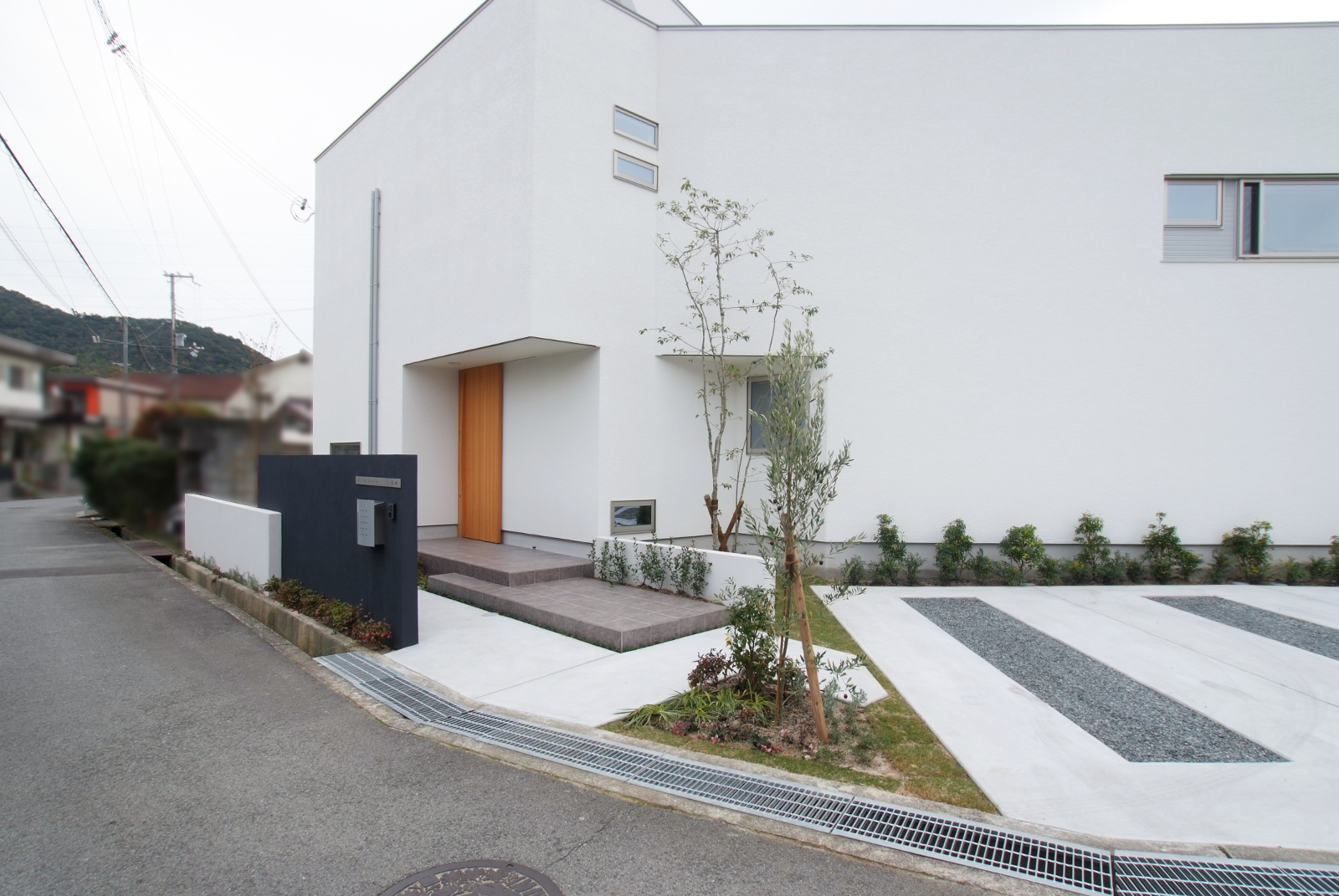 扇型の敷地の外辺に添い、庭を囲むように建物をくの字に配置